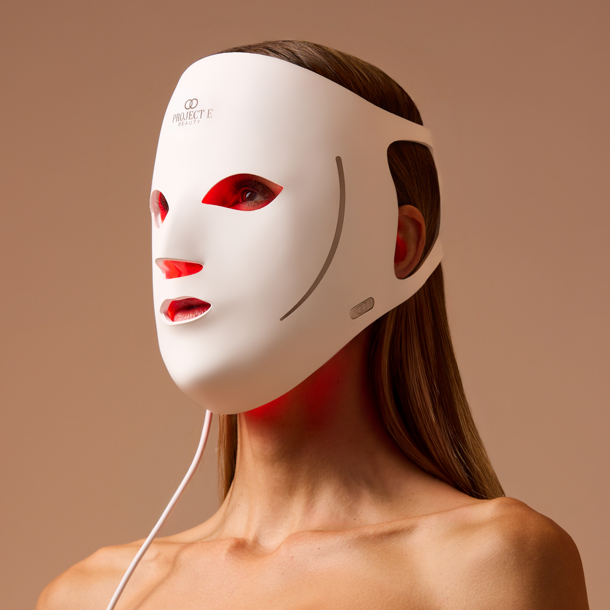 Kvinna med vit LumaLux Face V2 mask och synligt rött ljus inuti