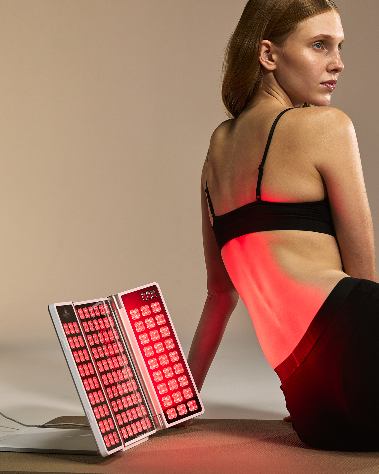 Woman targeting the back of her body with near-infrared light therapy for body wellness